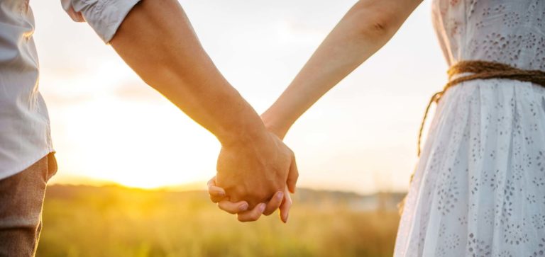 A couple holding hands at sunset
