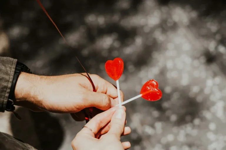 A couple holding two heart-shaped lollipops