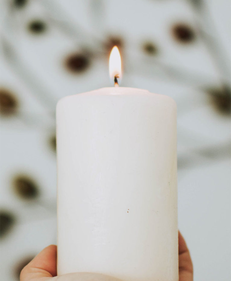 A lit candle held in two hands